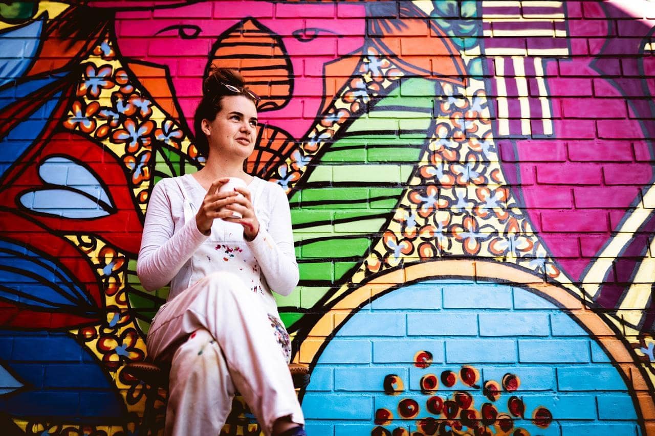 Meg Moore seated in front of one of her colourful murals